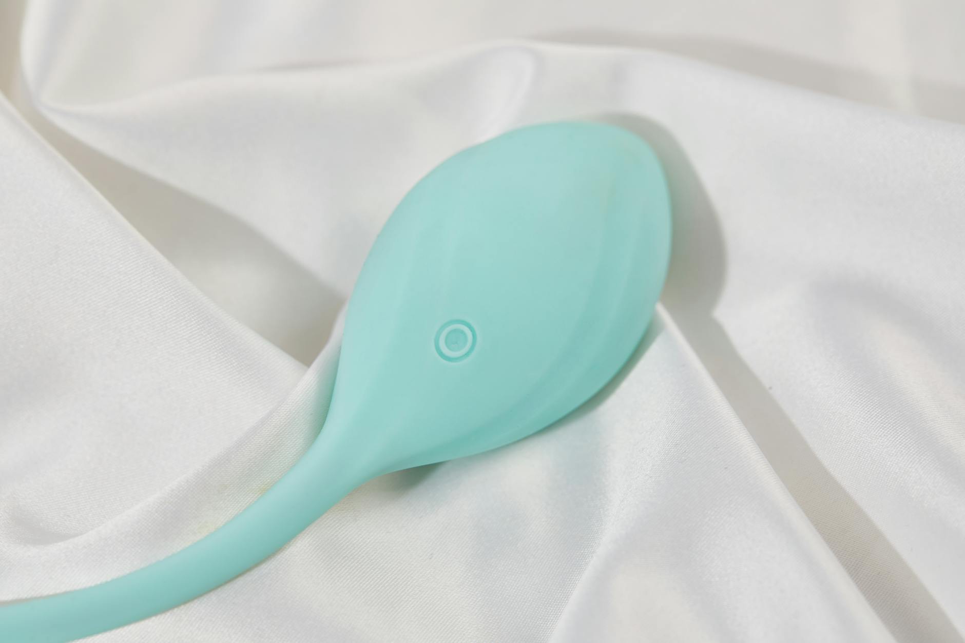 A teal silicone lemon vibrator on white silk, representing pleasure restoration
