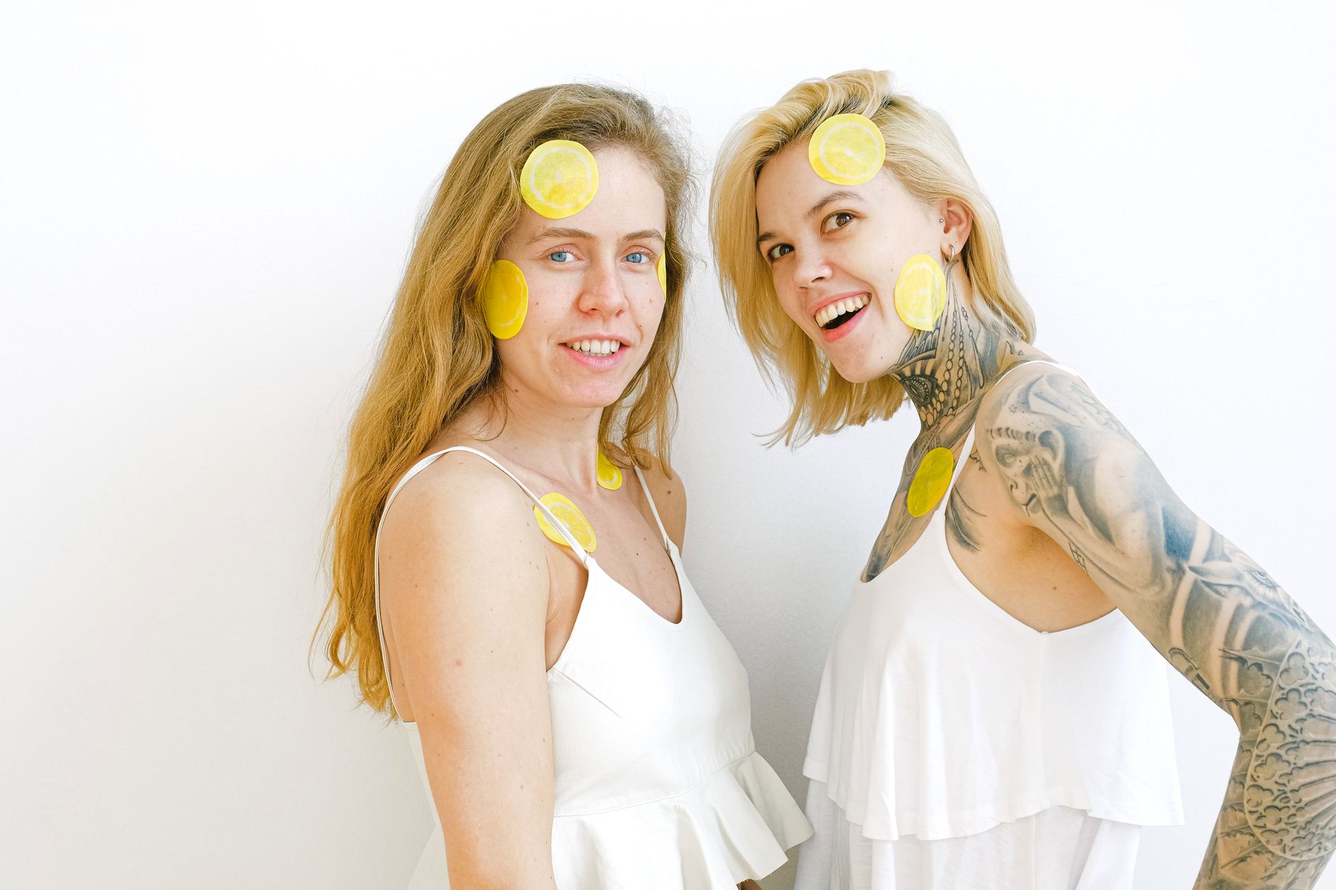 Due donne che sorridono e si divertono, con fette di limone sulla faccia.