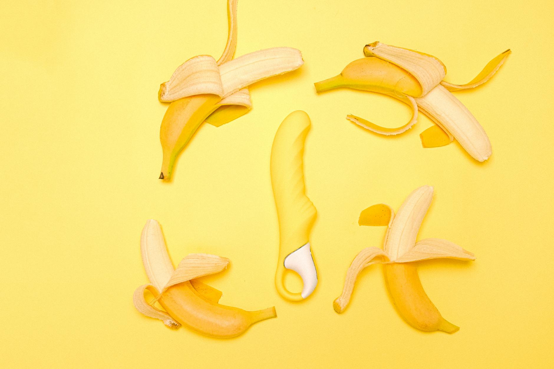 Yellow lemon-shaped clitoral vibrator surrounded by fresh lemons on a bright yellow background