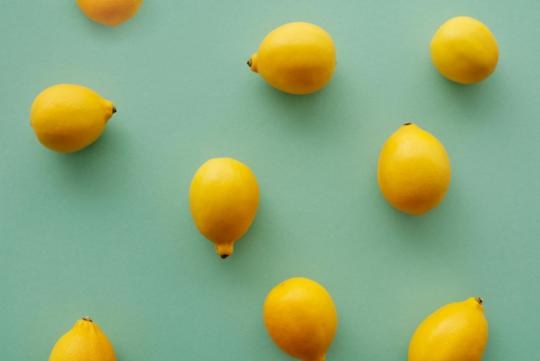 Yellow silicone vibrator surrounded by fresh fruit on a warm yellow background