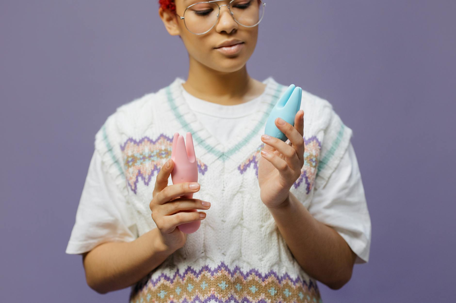 Donna che tiene in mano vibratori in silicone blu e rosa con uno sguardo contemplativo