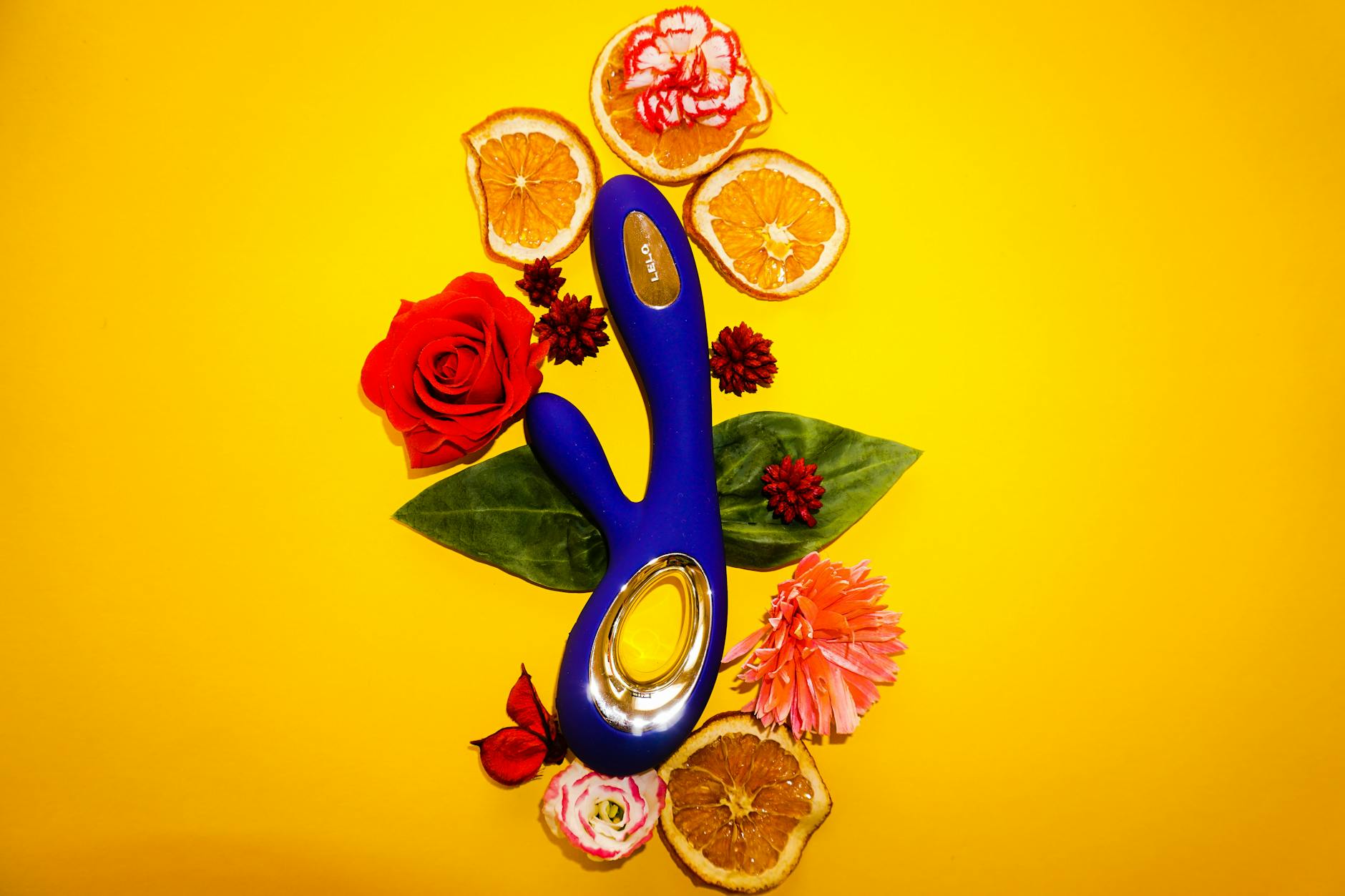 Hand reaching over a variety of colorful silicone clitoral vibrators arranged on a surface