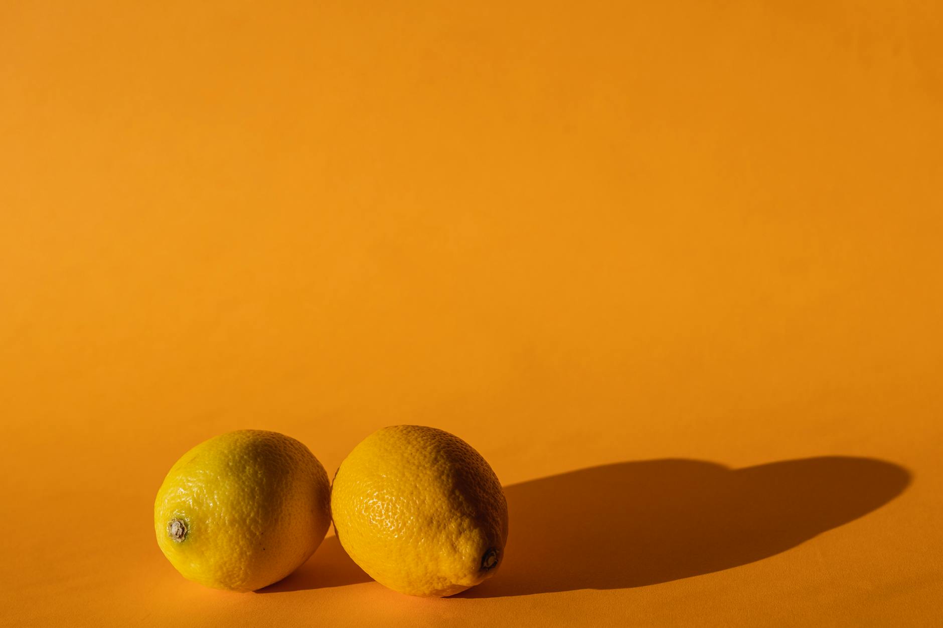 Ripe vivid lemons arranged on a bright yellow background, symbolizing the lemon vibrator's citrus-inspired design
